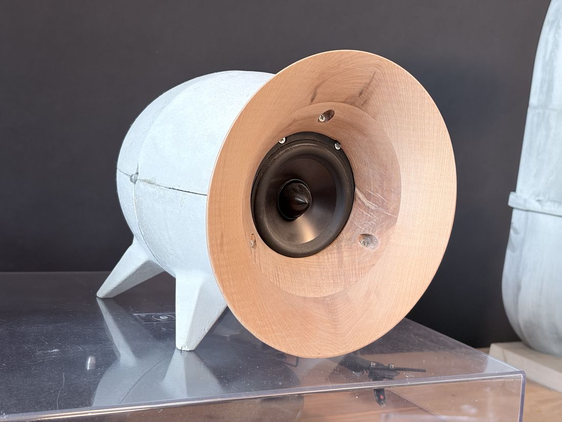Witte bolvormige luidspreker op driepotige poot met een houten hoorn-front rondom de driver